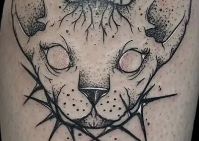 Tatouage style néo tribal d'un chat sphynx avec 2 couteaux