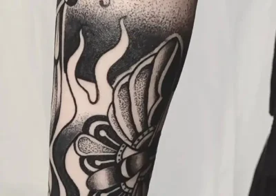 Tatouage en noir d'un papillon et dotwork