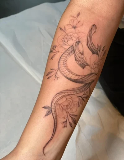 Tatouage sur l'avant bras représentant un serpent et des fleurs