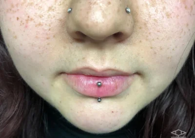 Jeune femme avec un bijou de piercing sur chaque narine et un piercing sur la lèvre inférieure