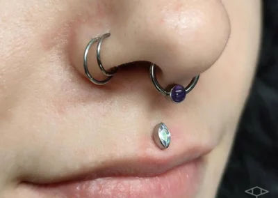Femme avec un double piercing sur la narine, ainsi qu'un medusa et un bijou de piercing au septum