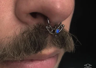 Homme avec une moustache qui porte un piercing réalisé sur le septum