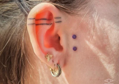 Oreille d'une jeune femme avec 2 piercing au niveau du lobe et un piercing au tragus
