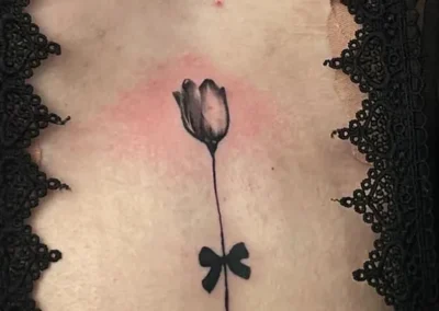 Tatouage sur le torse, d'une rose avec un noeud sur la tiqe
