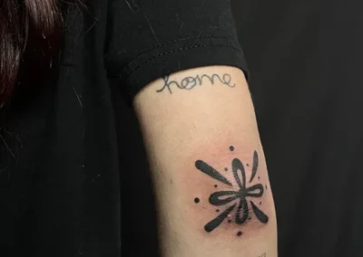 Tatouage sur le coude représentant une fleur graphique