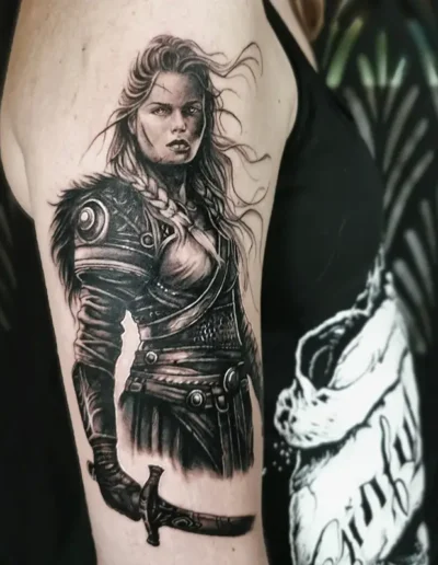 Tatouage femme guerrière ou valkyrie avec épée, style réaliste en noir et gris sur le bras