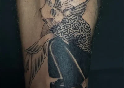 Tatouage d'un homme-oiseau ou d'Icare avec des ailes et un corps humain, en noir et gris, style illustratif, sur la jambe