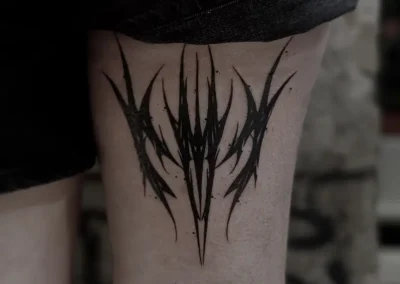 Tatouage abstrait noir aux formes pointues et style néotribal, sur la cuisse