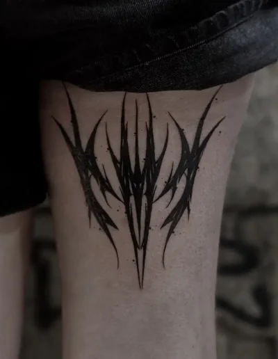 Tatouage abstrait noir aux formes pointues et style néotribal, sur la cuisse