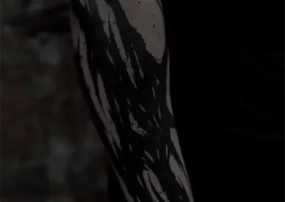 Tatouage abstrait noir et gris avec des formes déchiquetées et pointues, style blackwork, sur le bras