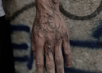 Tatouage abstrait style cyber sigilism ou blackwork, avec des formes pointues et linéaires en noir sur la main