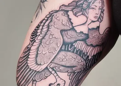 Tatouage de créature fantastique, femme-aigle avec de grandes plumes, en nuances de gris