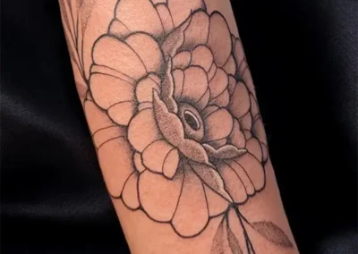Tatouage d'une fleur type pivoine aux contours nets et ombrages doux, en nuances de gris