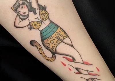 Tatouage coloré sur le bras, d'une femme pin-up avec oreilles de chat et maillot de bain léopard, style vintage