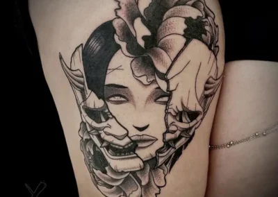 Tatouage d'une femme avec un visage de Geisha ou un masque japonais, des fleurs de pivoine et de chrysanthème, style réaliste en noir et gris sur la cuisse