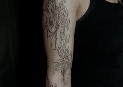Tatouage néo-tribal fineline sur le bras, réalisé par l’artiste @petit.croco.tattoo