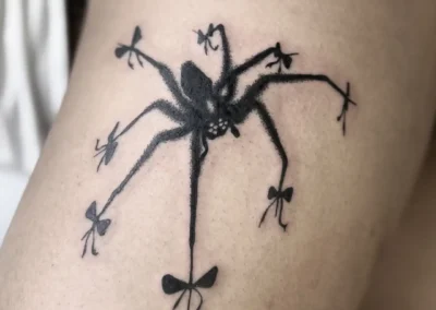 Tatouage araignée noire aux pattes ornées de petits nœuds