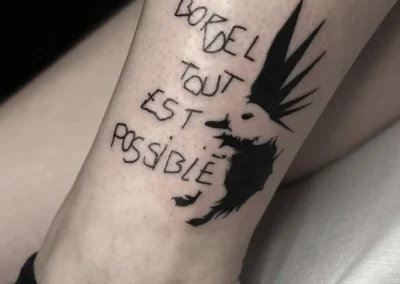 Tatouage cheville 'BORDEL TOUT EST POSSIBLE' avec illustration punk