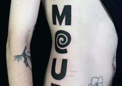 Tatouage flanc homme 'AMOUR' en grosses lettres noires avec spirale