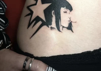 Tatouage noir graphique d'un portrait de femme de profil avec une étoile, style punk et alternatif