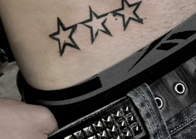 Tatouage sur la hanche de trois étoiles aux contours noirs graphiques