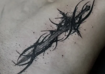 Tatouage sur l'abdomen représentant une épée stylisée mêlée à des motifs cybersigilism noirs et des projections d'encre