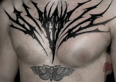 Tatouage imposant sur le torse de style cybersigilism aux lignes noires symétriques et pointues