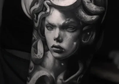 Tatouage biceps Medusa réaliste en noir et gris avec serpents détaillés réalisé chez ARXE Lyon
