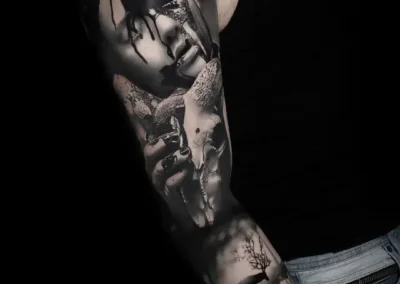 Tatouage manchette complet réaliste noir et gris : visage femme, crâne cerf, fleurs et forêt réalisés chez ARXE Lyon