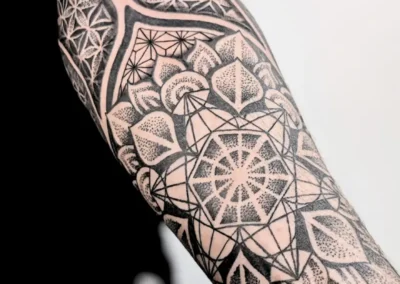 Tatouage ornemental et géométrique noir sur l'avant bras, motif mandala, lignes symétriques et dotwork