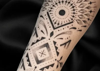 Tatouage ornemental et géométrique noir sur l'avant bras, motif mandala, lignes symétriques et dotwork