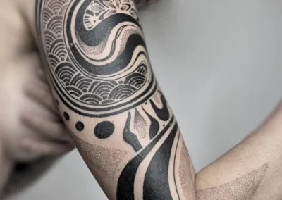 Tatouage ornemental et géométrique noir sur le bras, motif mandala, lignes symétriques et dotwork