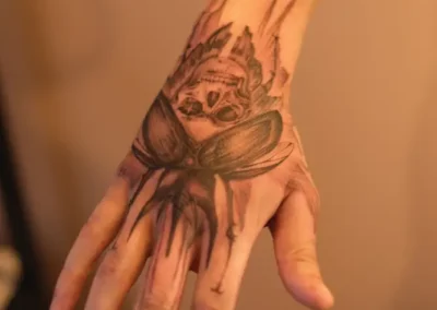 Tatouage d'une tête de mort, ornée d'ailes, sur le dessus de la main